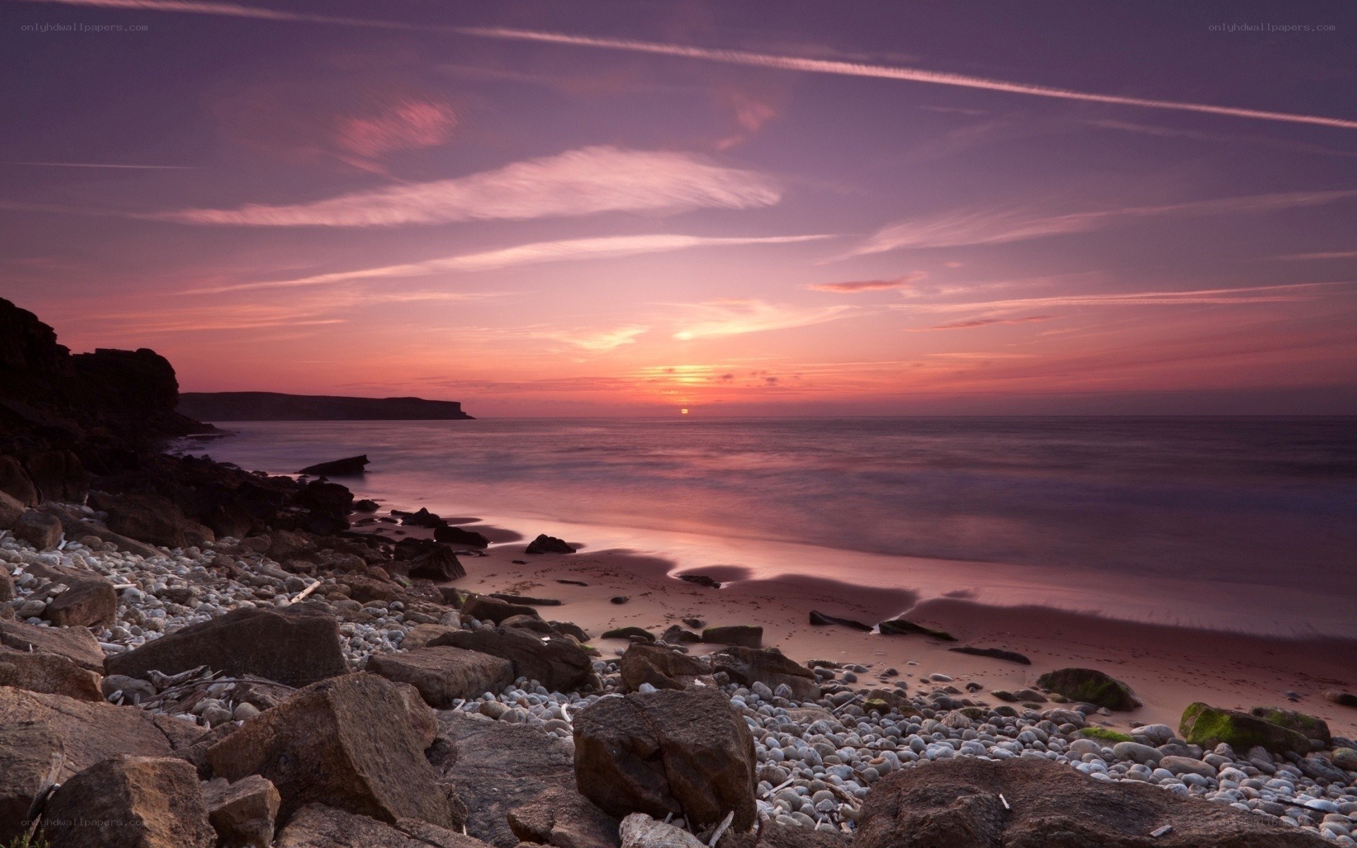 Purple sunset over rocky beach