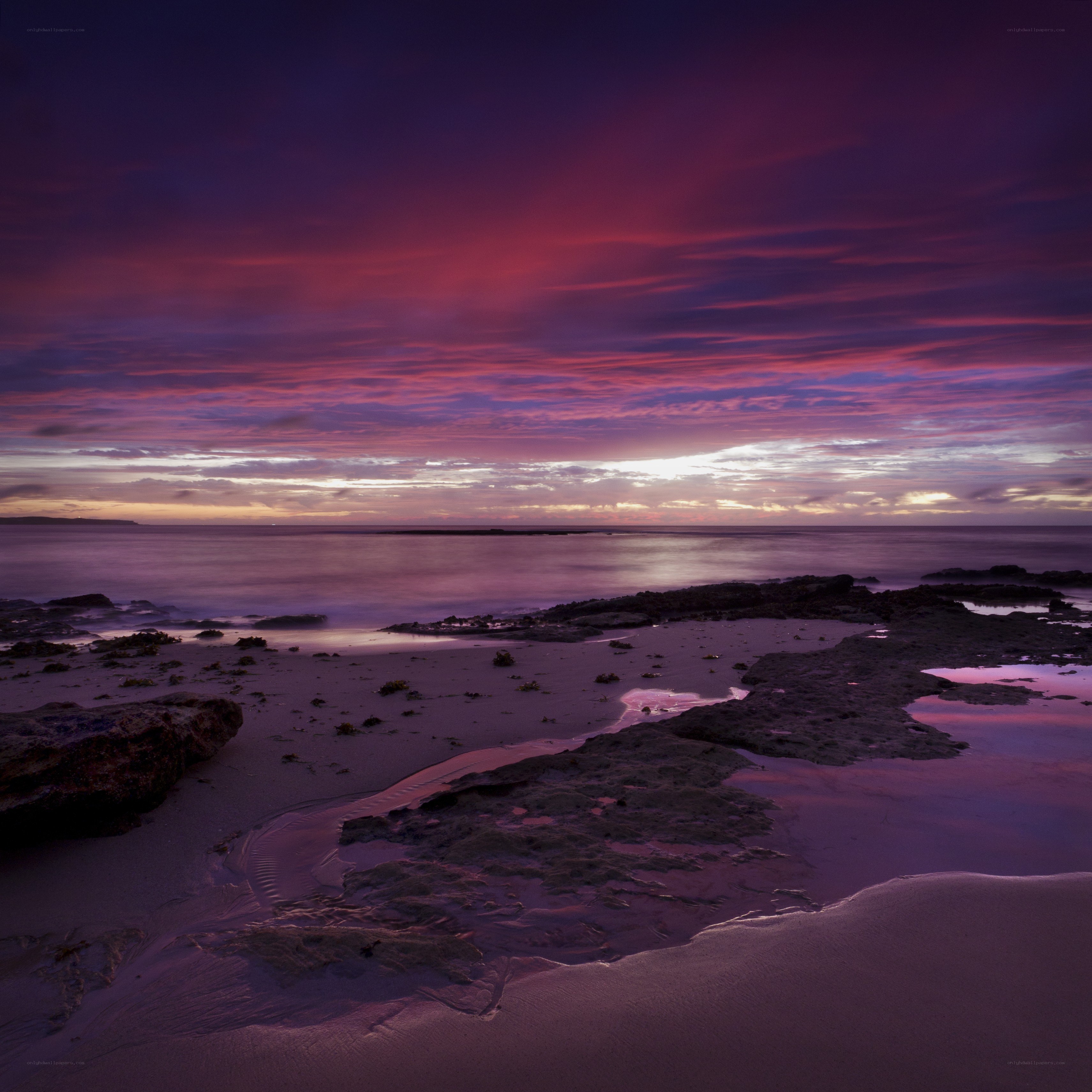 Purple sunset over rocky beach