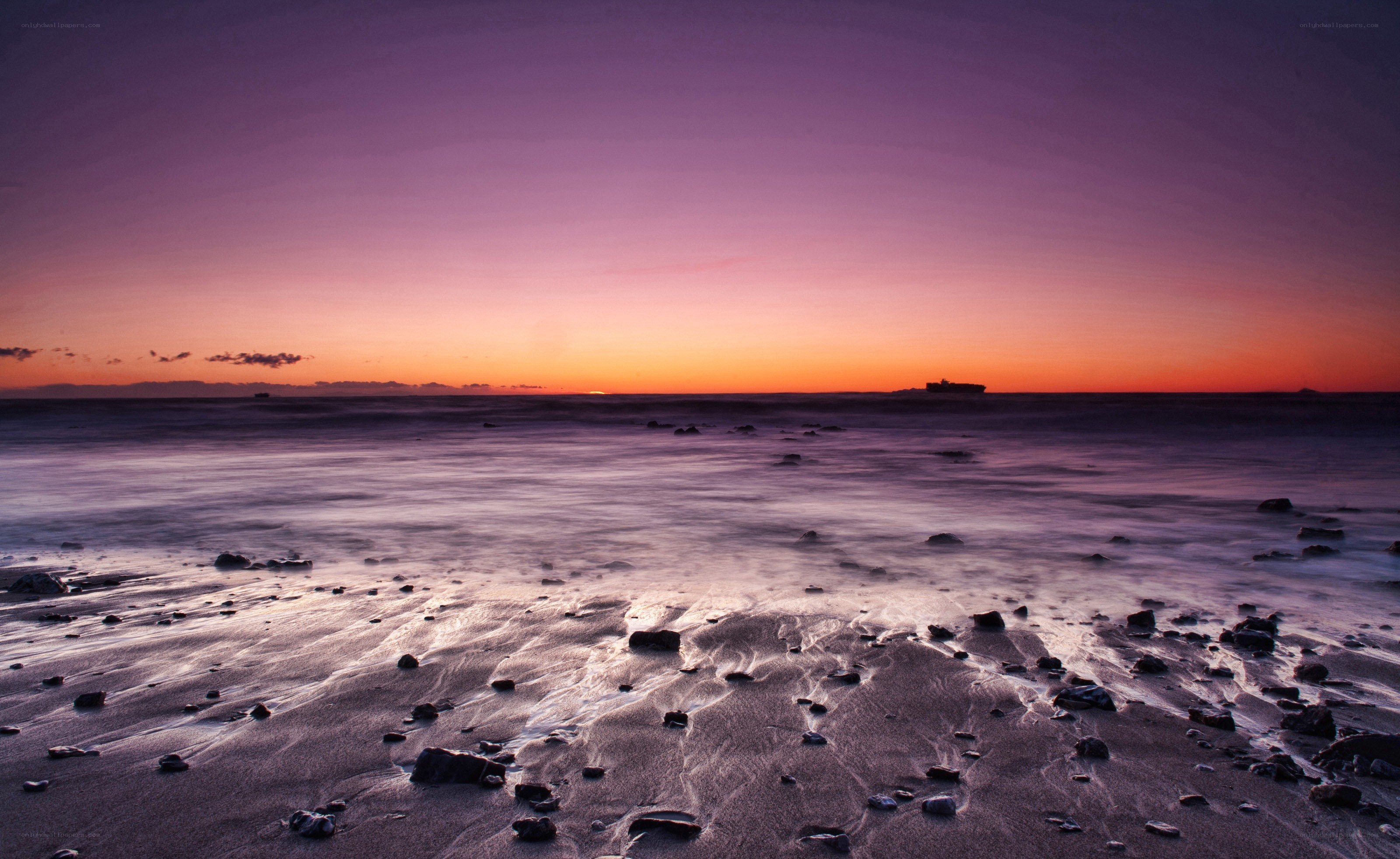 Purple sunset over rocky beach