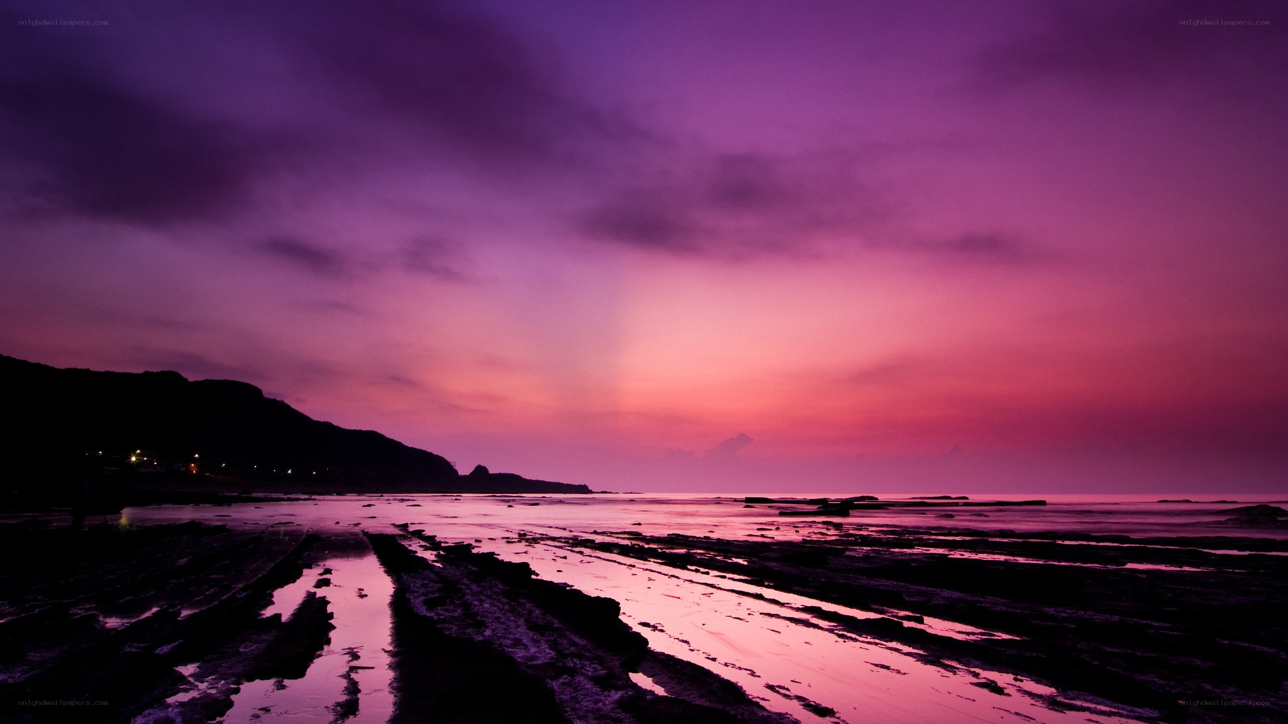 Purple sunset over rocky beach