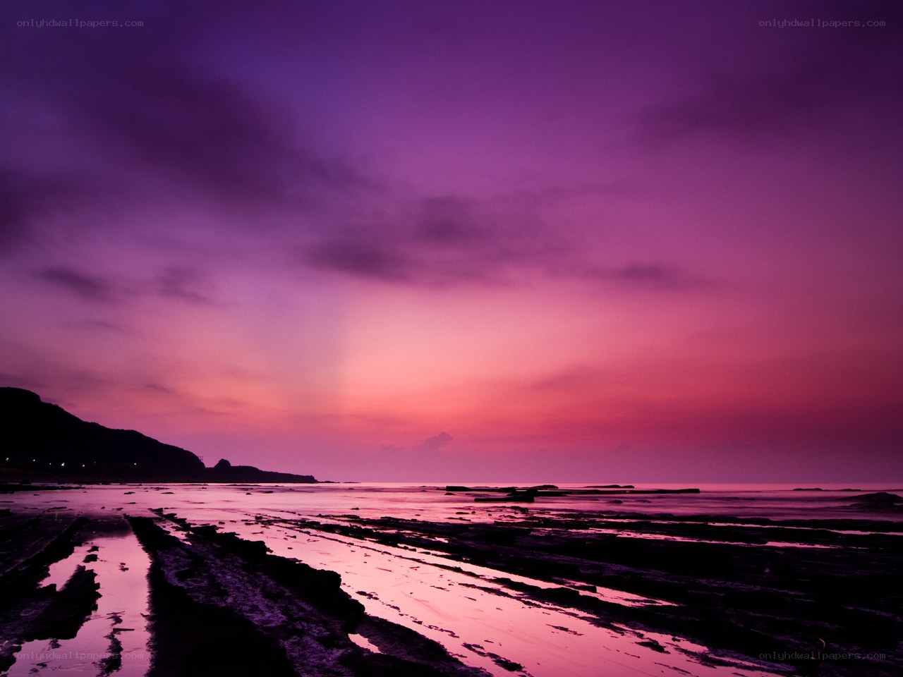 purple sunset over rocky beach
