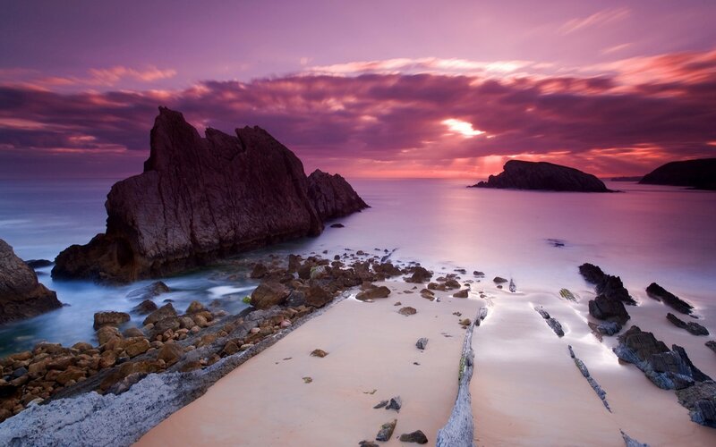 Purple sunset over rocky beach