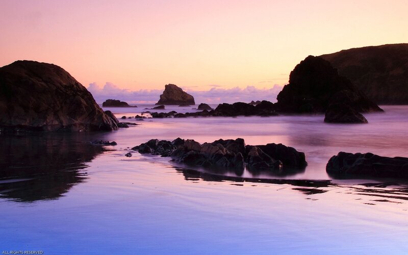 Purple sunset over rocky beach