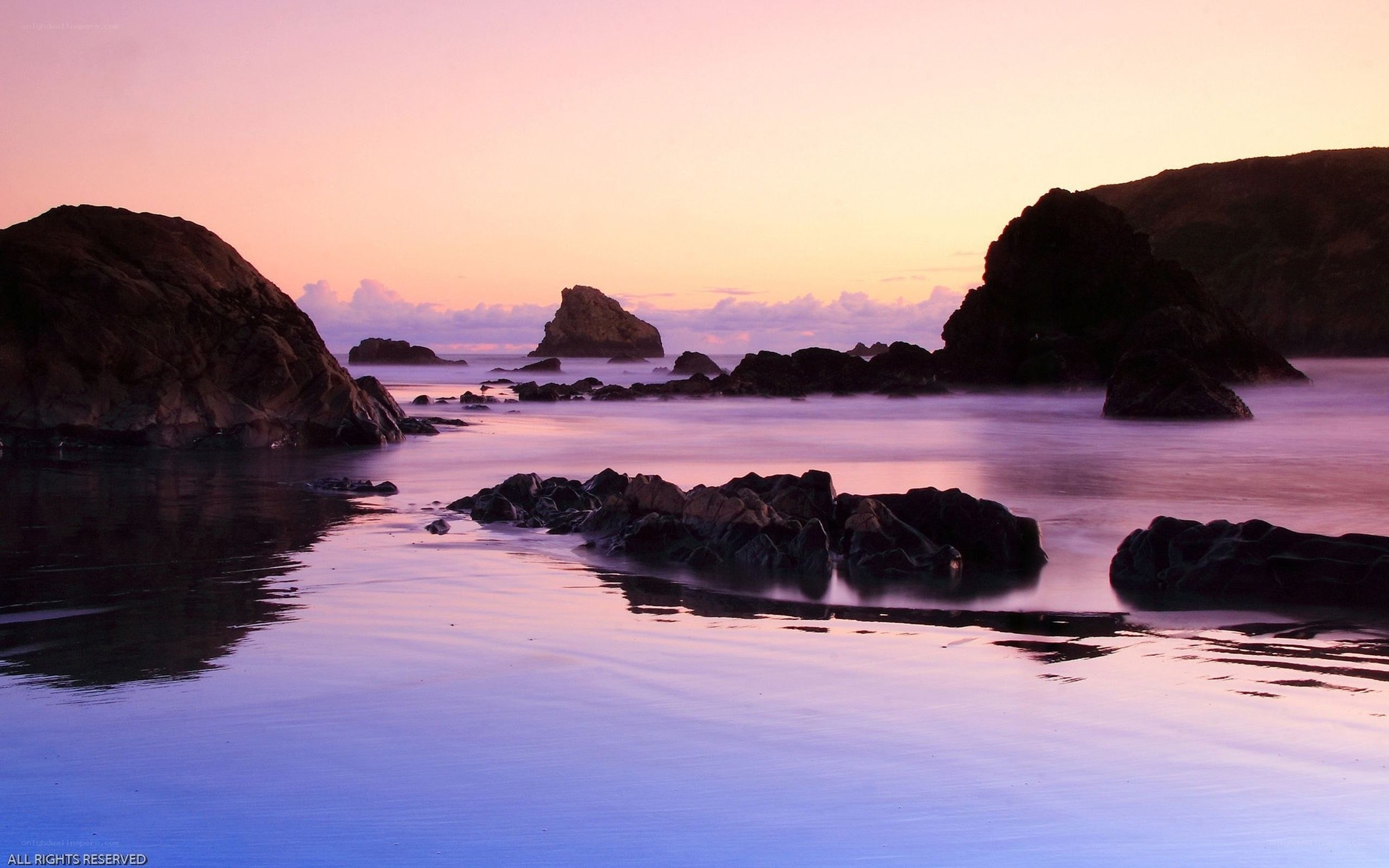 Purple sunset over rocky beach