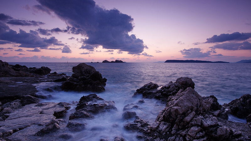 Purple sunset over rocky coast