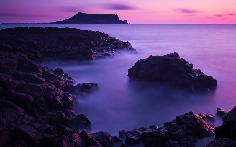 Purple sunset over rocky coast