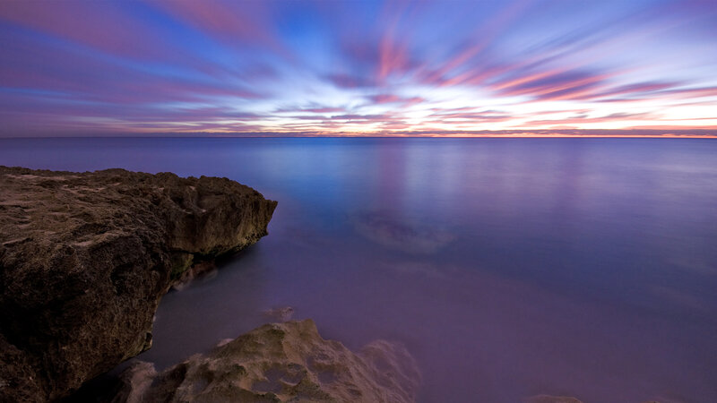 Purple sunset over rocky coast
