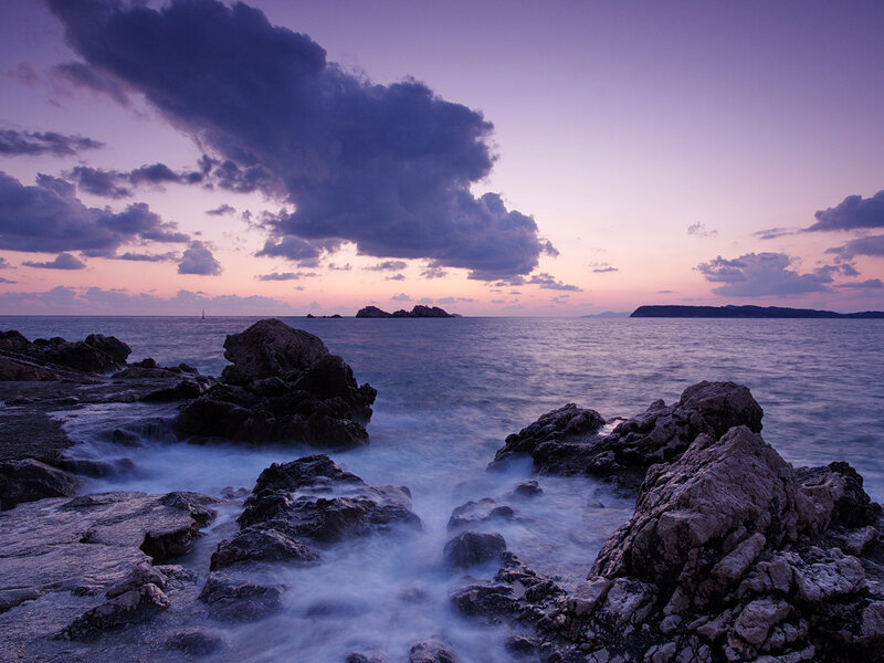 Purple sunset over rocky coast