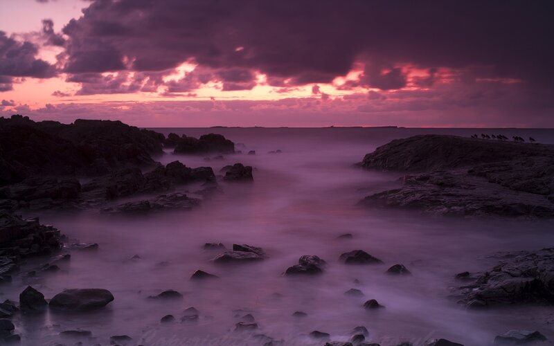 Purple sunset over rocky coast