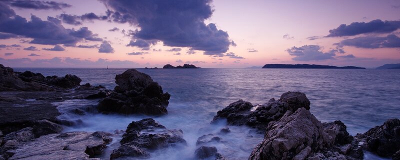 Purple sunset over rocky coastline