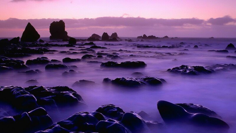 Purple sunset over rocky shore