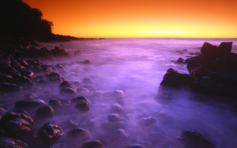 Purple sunset over rocky shore