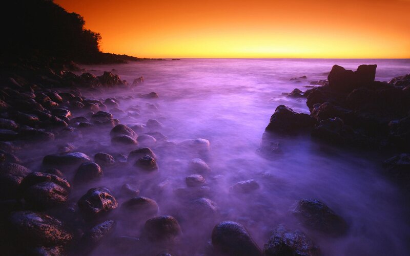 Purple sunset over rocky shore