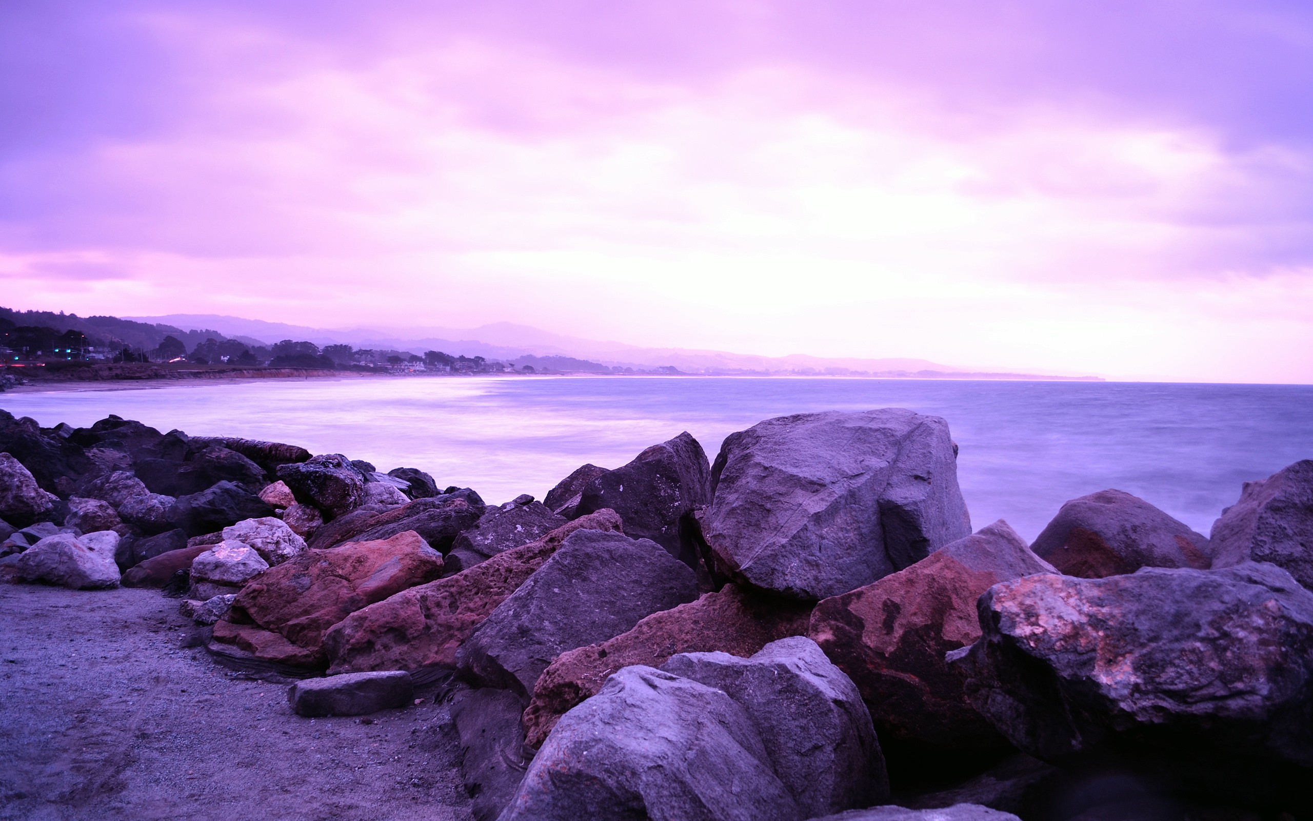 Purple sunset over rocky shore