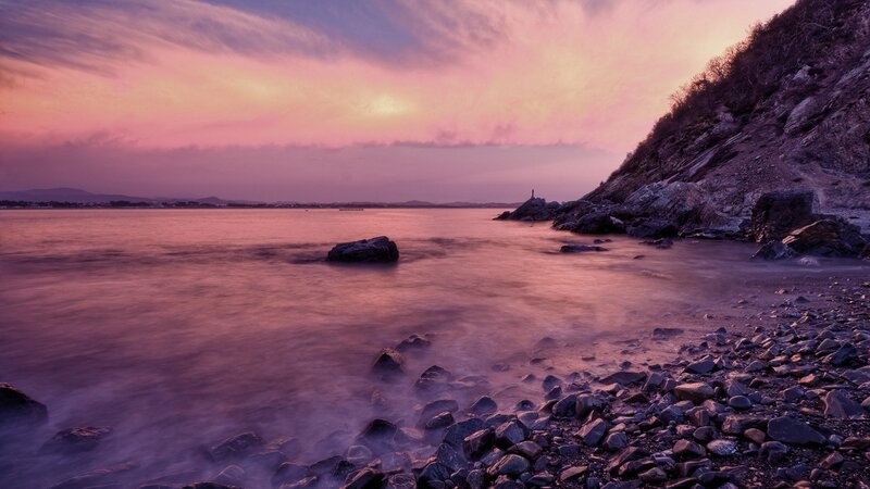 Purple sunset over rocky shore