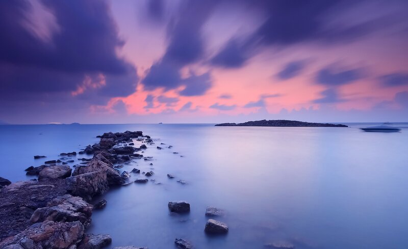 Purple sunset over rocky shore
