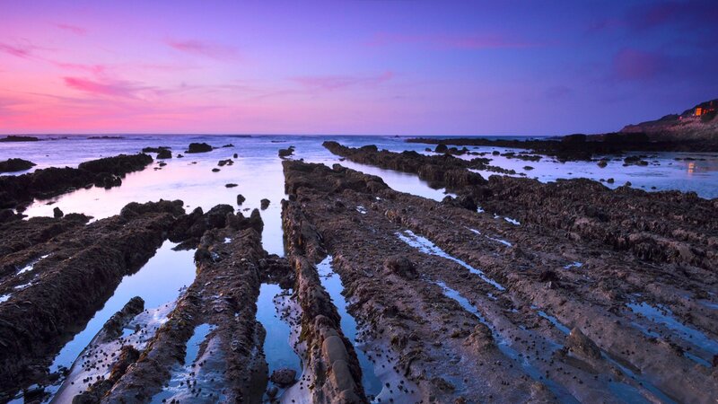 Purple sunset over rocky shore