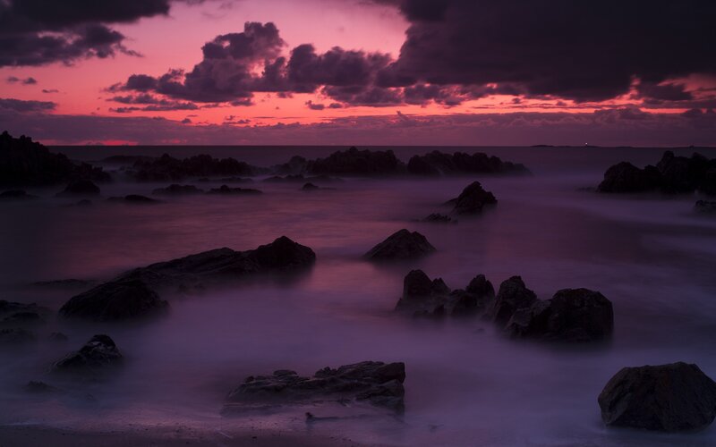 Purple sunset over rocky shore