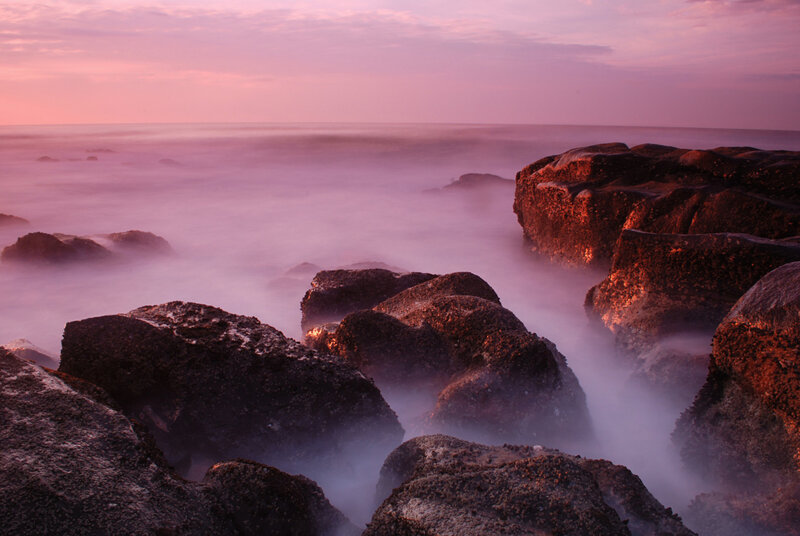 Purple sunset over rocky shore
