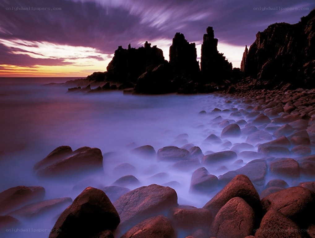 Purple sunset over rocky shore