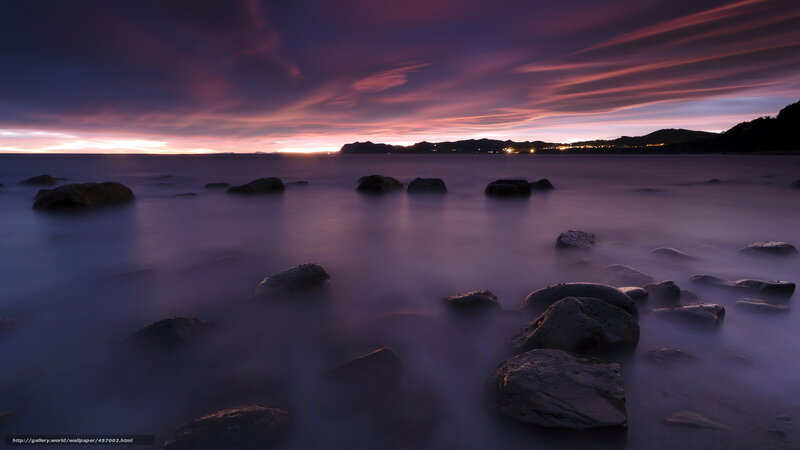 Purple sunset over rocky shore