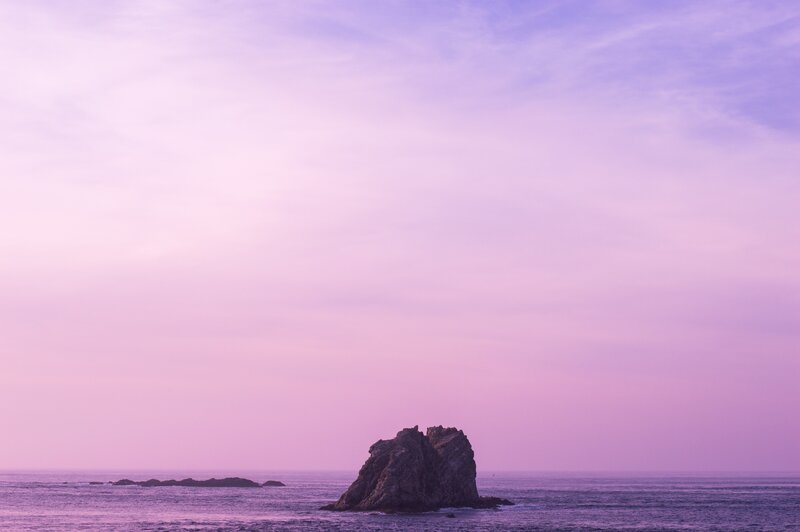 Purple sunset over sea rock