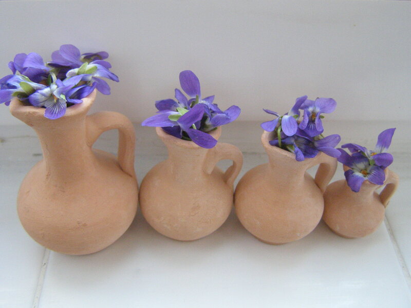 Purple violets in clay pitchers