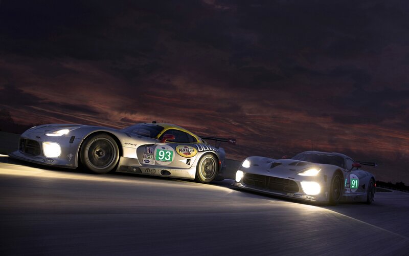 Race cars on a track at dusk