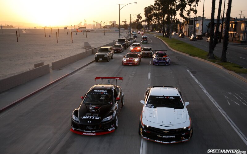 Race cars on coastal road at sunset