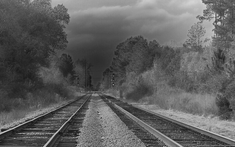 railroad tracks under stormy sky
