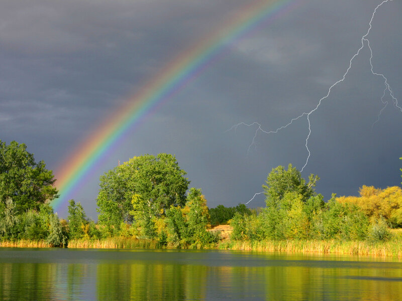 Rainbow and lightning over a lake