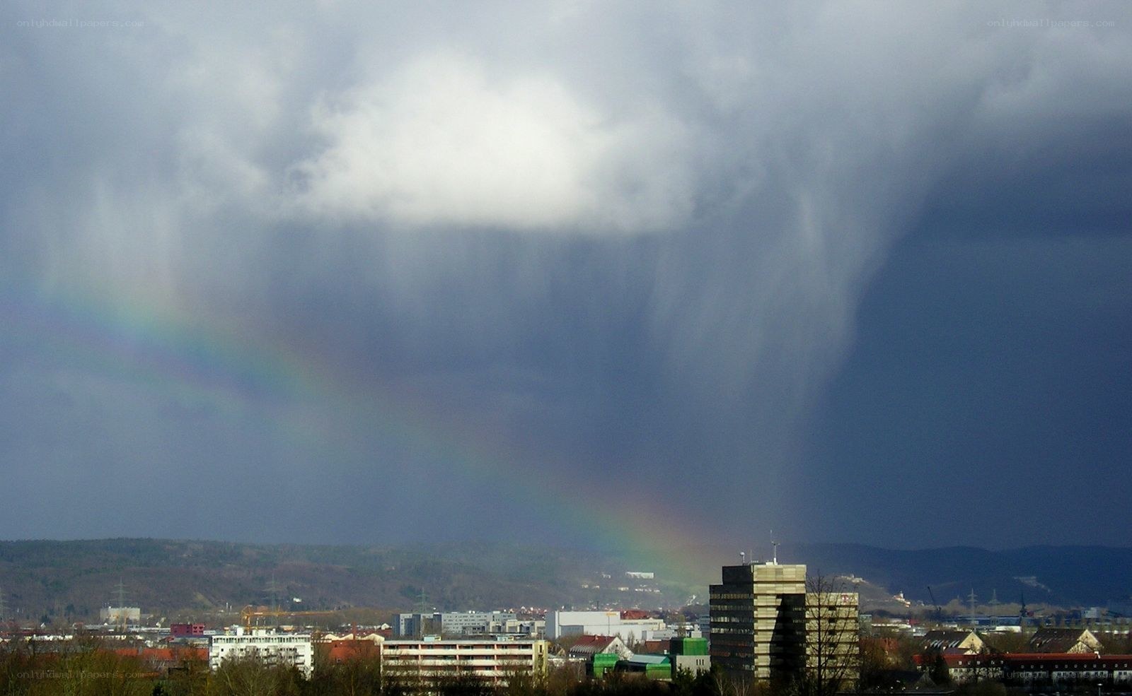 Rainbow over city with storm