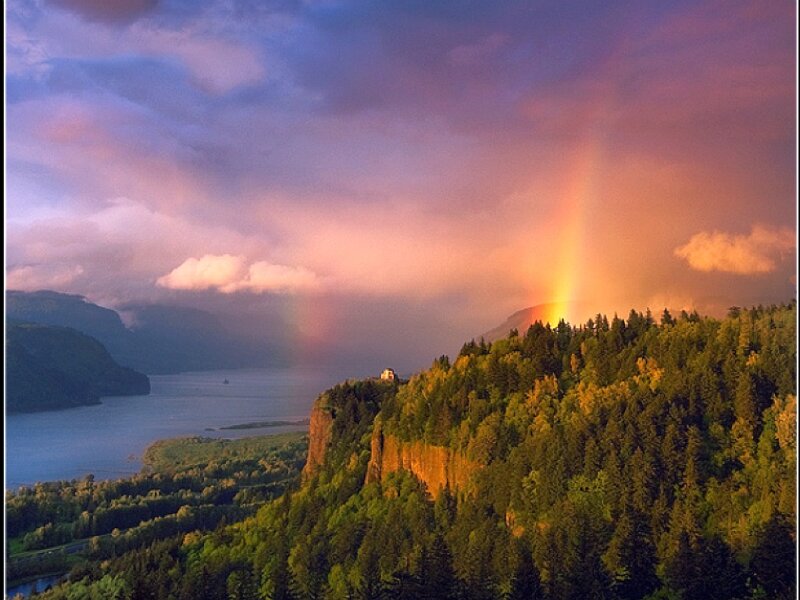 Rainbow over forested cliffs