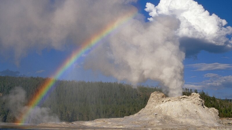 Rainbow over geyser eruption