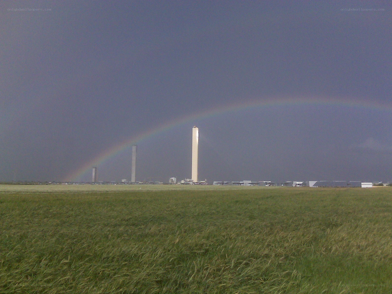 Rainbow over industrial towers