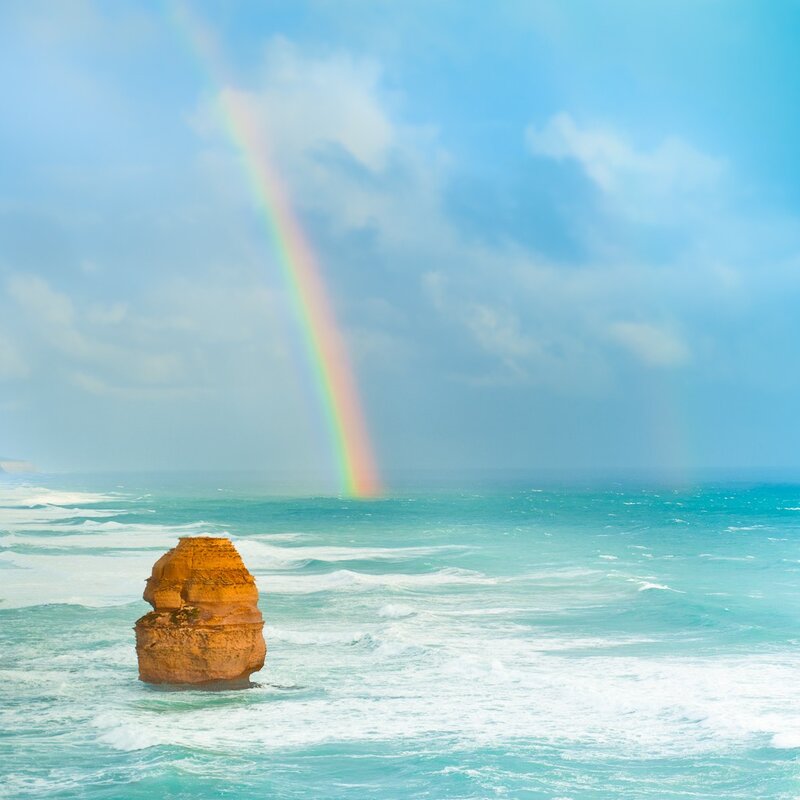 Rainbow over ocean rock formation