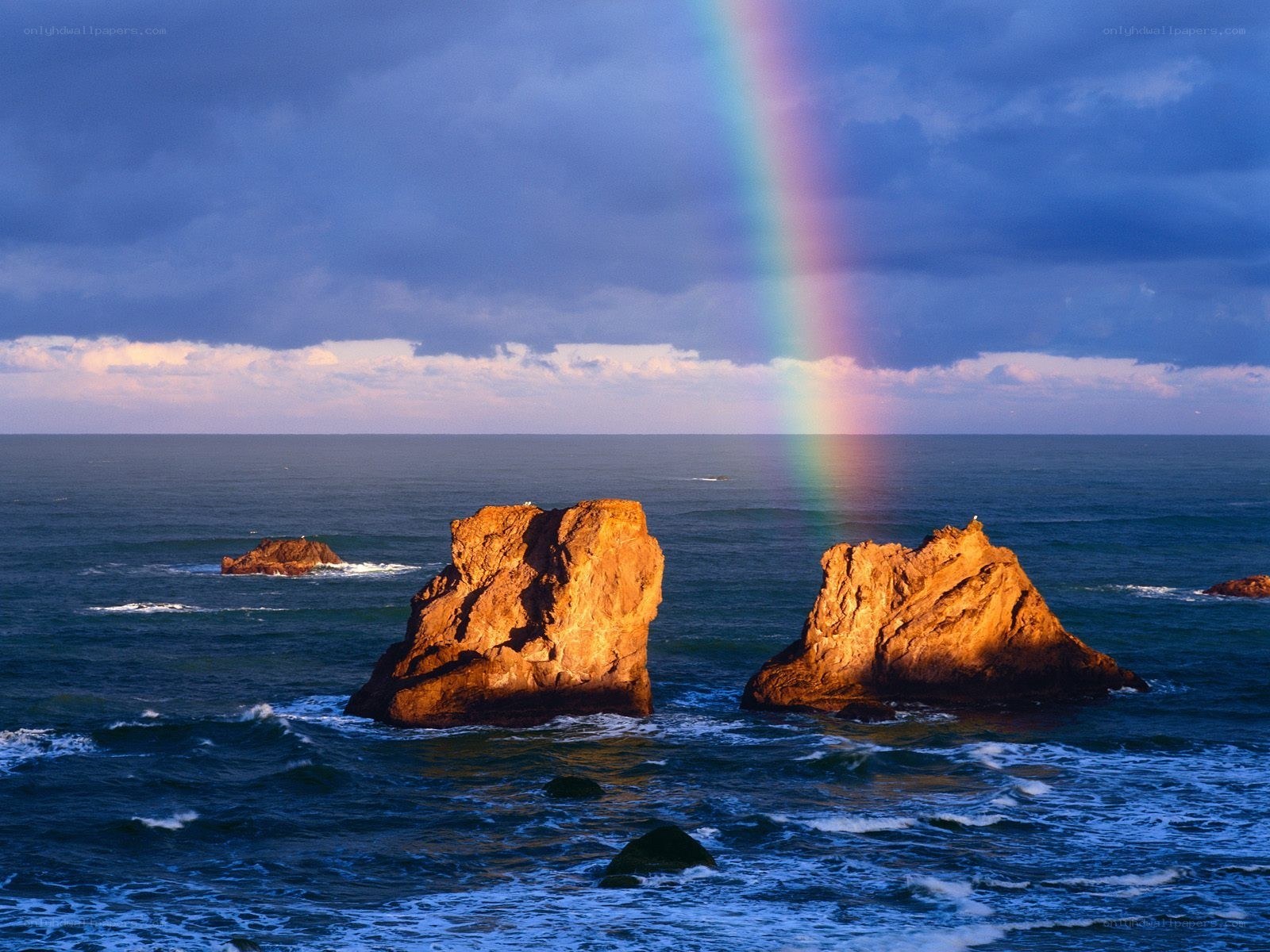 Rainbow over ocean rocks