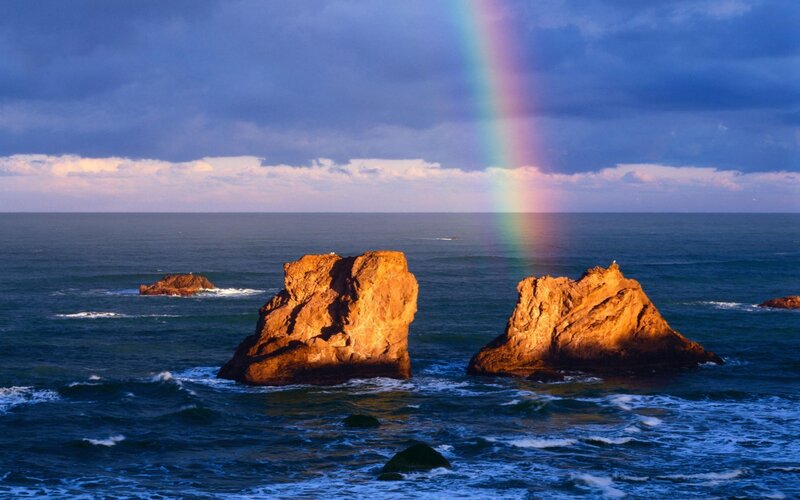 Rainbow over ocean rocks