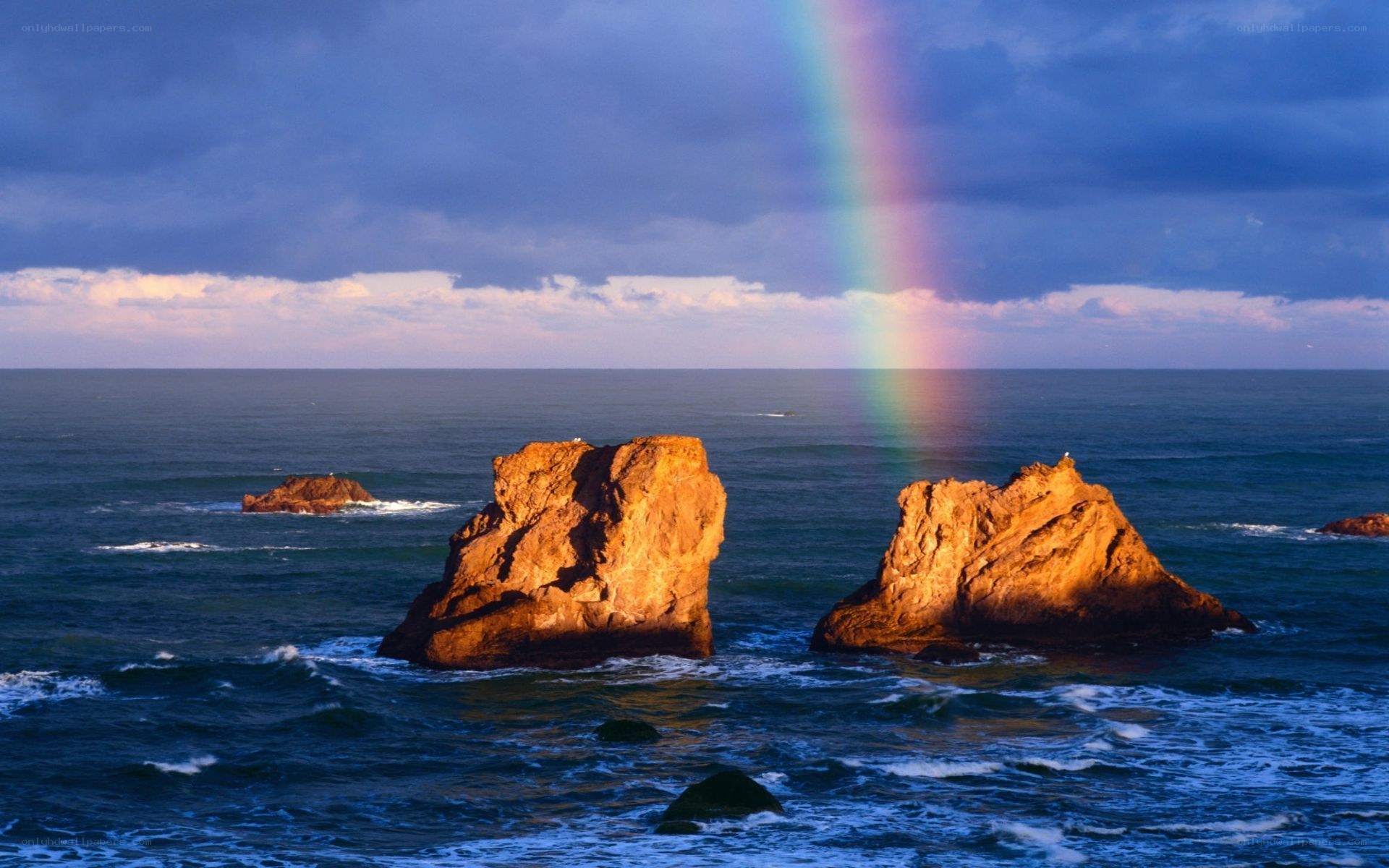 Rainbow over ocean rocks