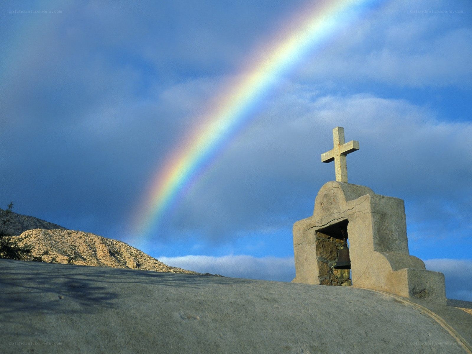 Rainbow over stone cross