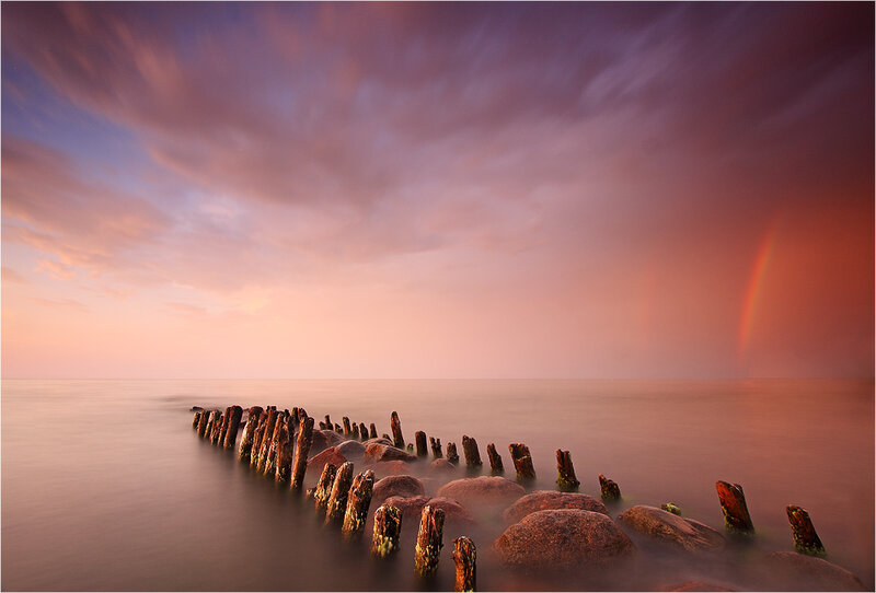 Rainbow over wooden breakwater