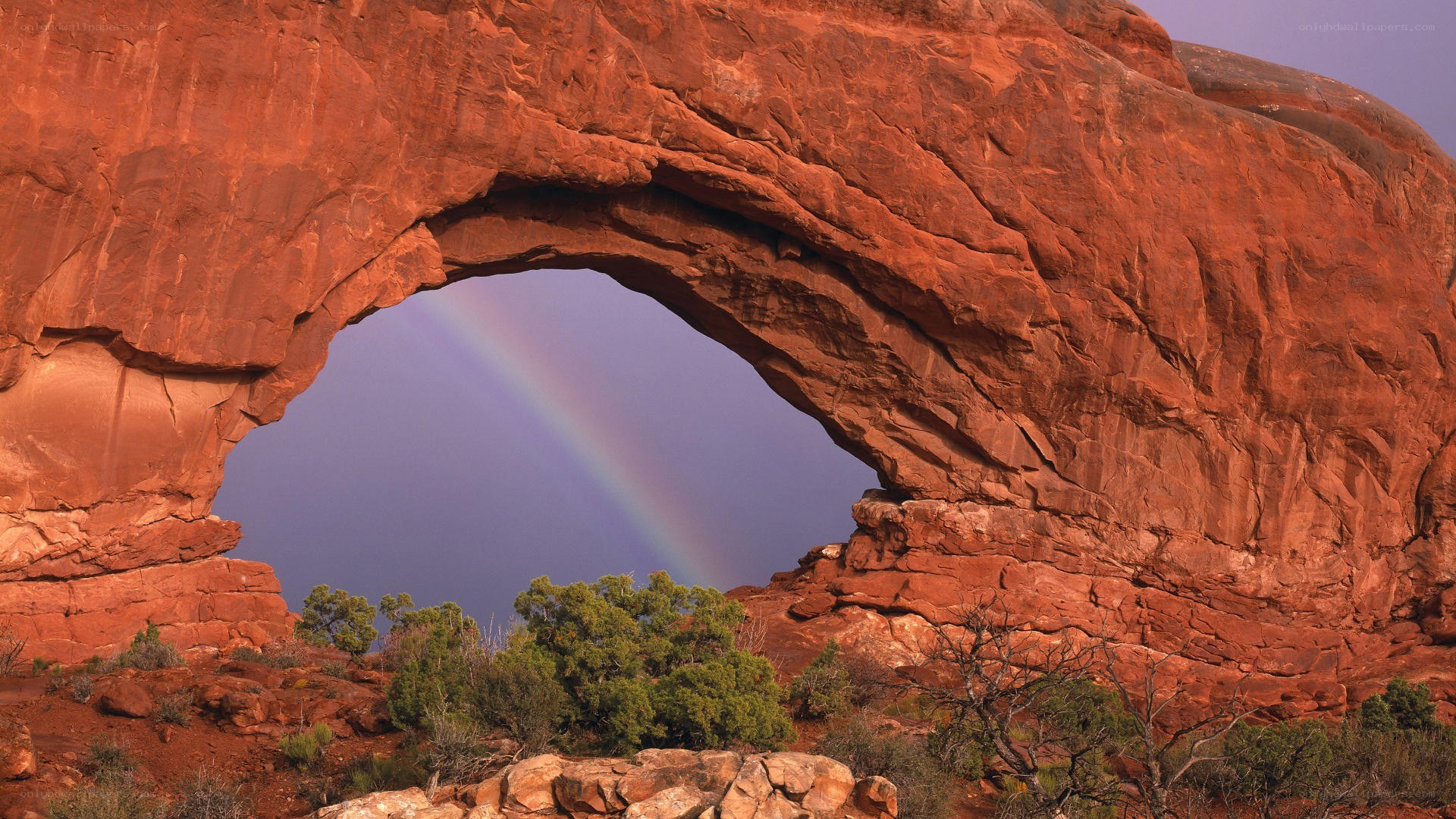 Rainbow through red rock arch