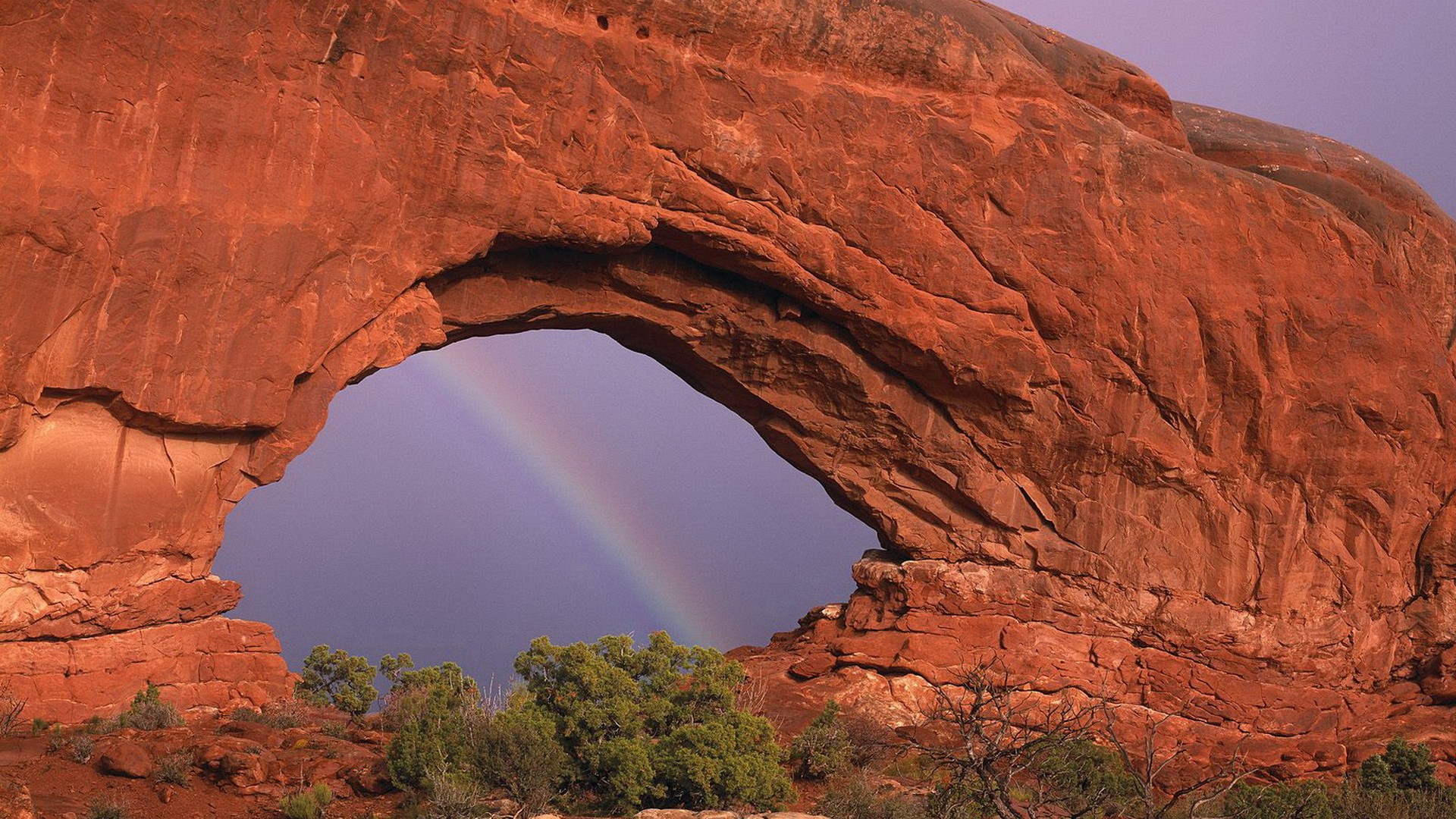 Rainbow through red rock arch
