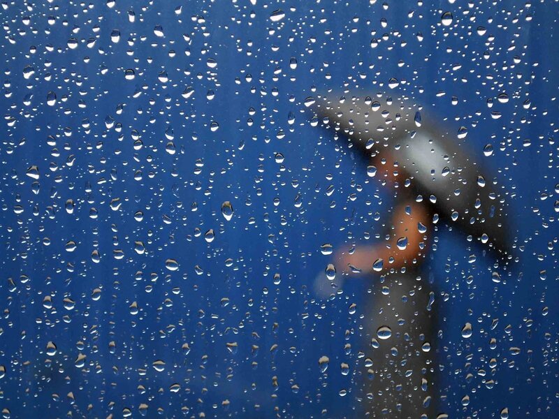 Raindrops on a window with a person holding an umbrella