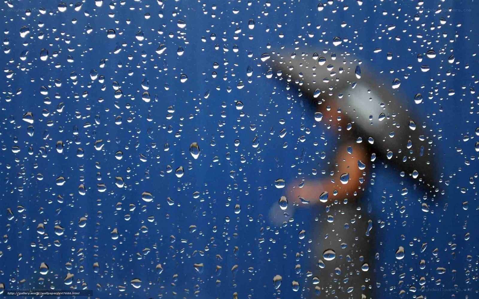 Raindrops on a window with a person holding an umbrella