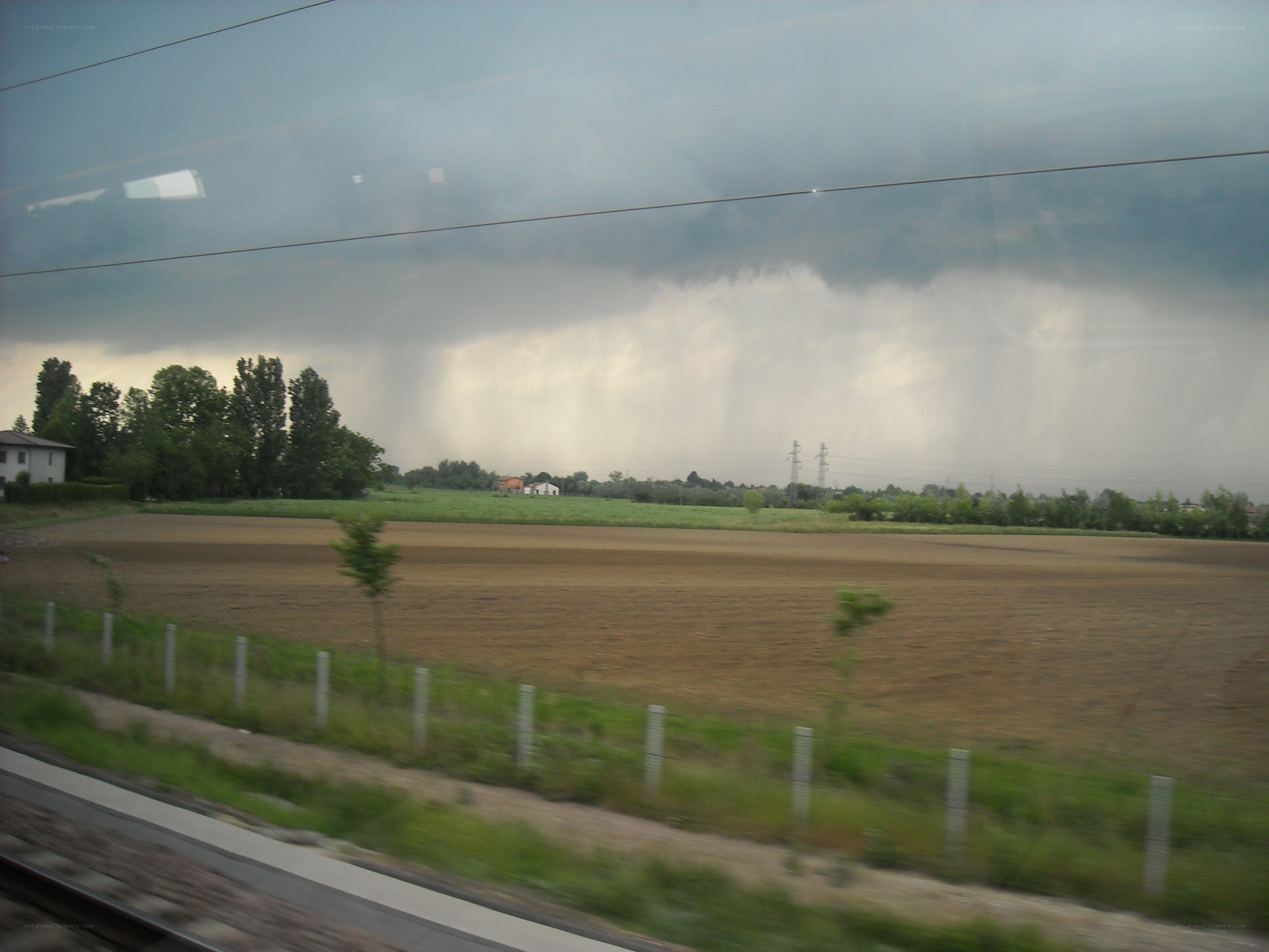 rainstorm over farmland from train