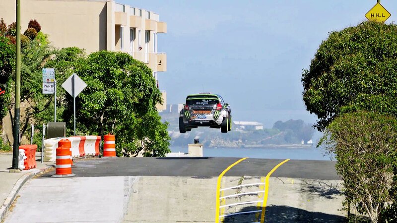 Rally Car in Mid-air — Green, Dramatic, Afternoon, Photograph, Building