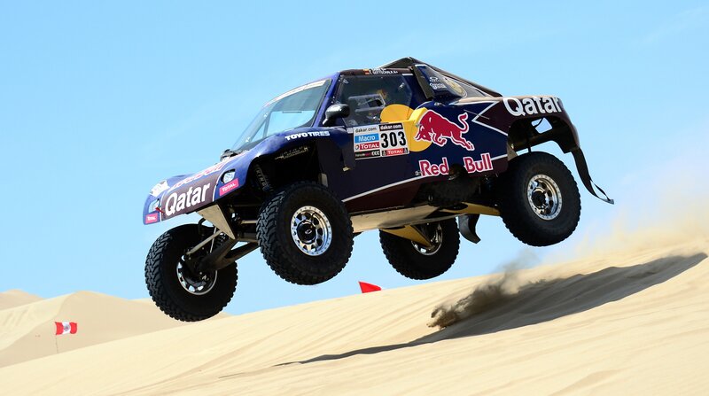 Rally car jumping over dune