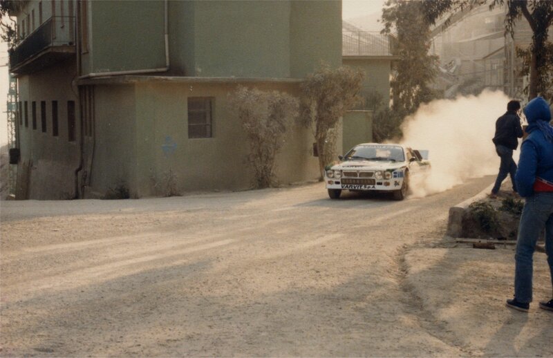 Rally Car on Dirt Road — Brown, Dynamic, Afternoon, Photograph, Building