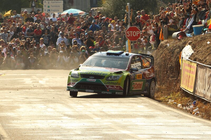 Rally car racing on a dusty road